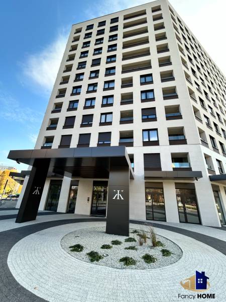 Magas épület a Kárpát utcában, Poprádon, modern bejárattal és íves járdákkal.