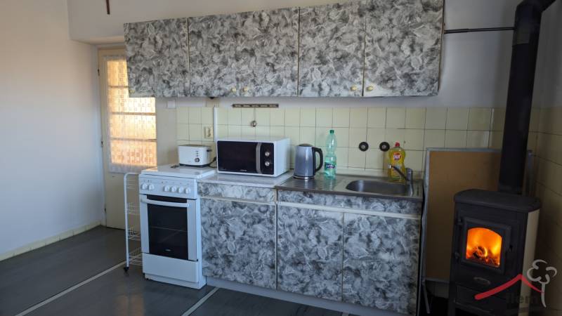 Konyha csempével, tűzhellyel és kandallóval egy családi házban, fa dekoros padlóval.