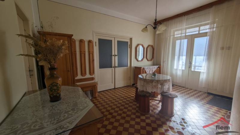 Családi ház belső tere színes csempével, virágvázával és függönyökkel.