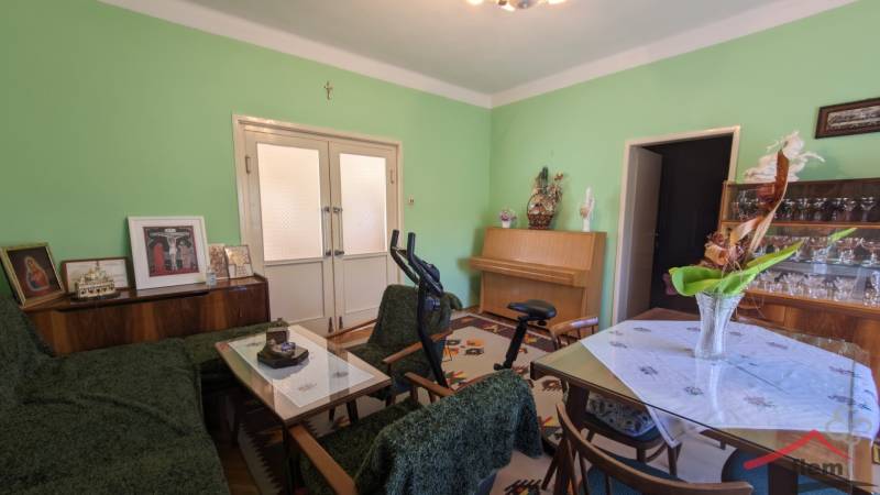 Nappali a családi házban bútorokkal, edzőfelszereléssel és zöld falakkal.