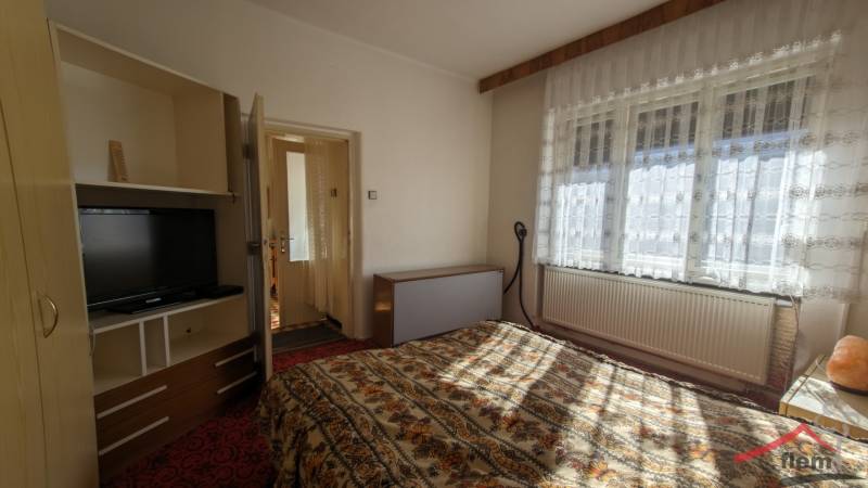 Hálószoba családi házban, televízióval és virágmintás ágyneművel.