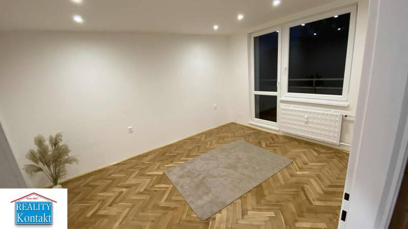 Szoba egy egyszobás lakásban fa dekorációjú padlóval és nagy ablakkal.