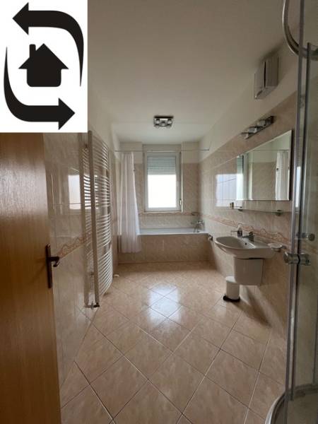 Fürdőszoba egy háromszobás lakásban káddal, üveg zuhanykabinnal és világos csempékkel.