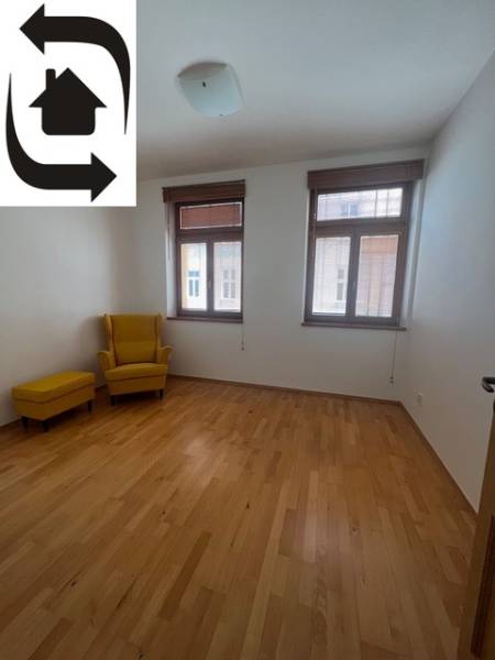 Szoba sárga fotellel és fa dekorációjú padlóval egy négy szobás lakásban.