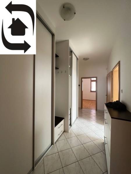 Keskeny folyosó egy négy szobás lakásban fehér szekrényekkel és csempével.