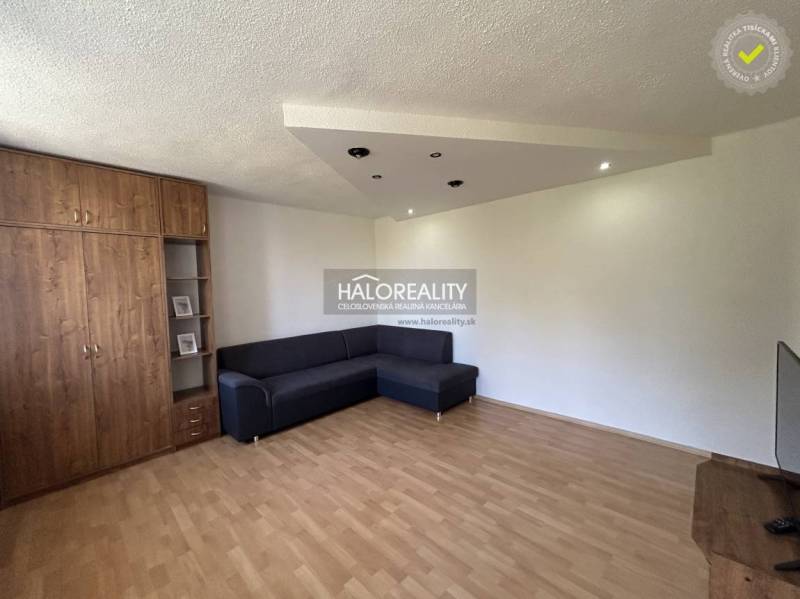 Nappali szoba fa szekrénnyel, kanapéval egy egyszobás lakásban, kellemes légkör.