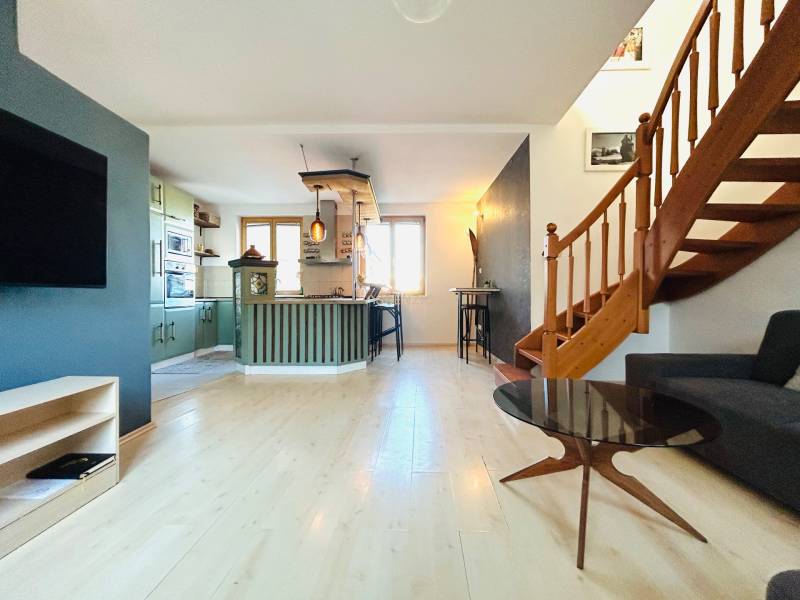 Nappali egy kétszobás lakásban konyhával és lépcsővel, fa dekoros padlóval.