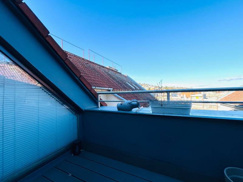 Fedett terasz egy 2 szobás lakásban, kilátással a házak tetejére és a tiszta égre.