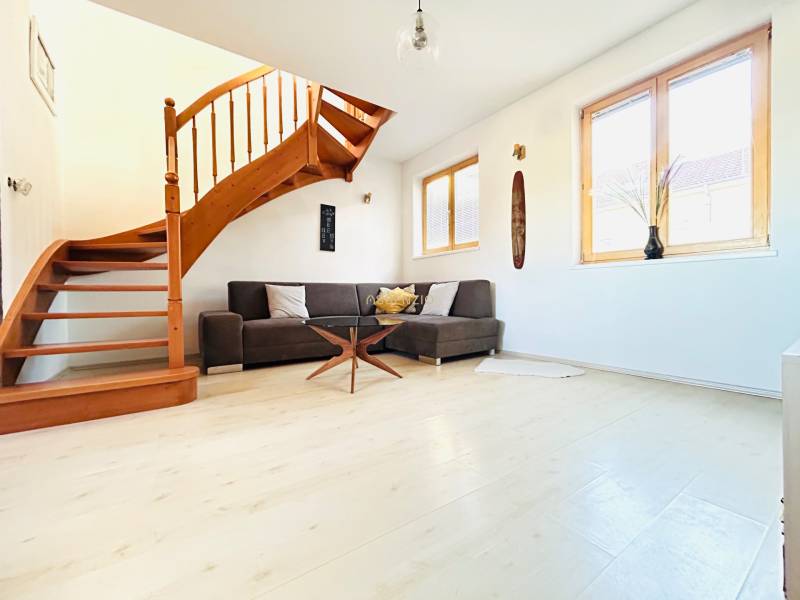 Nappali egy kétszobás lakásban csigalépcsővel és fa dekoros padlóval.