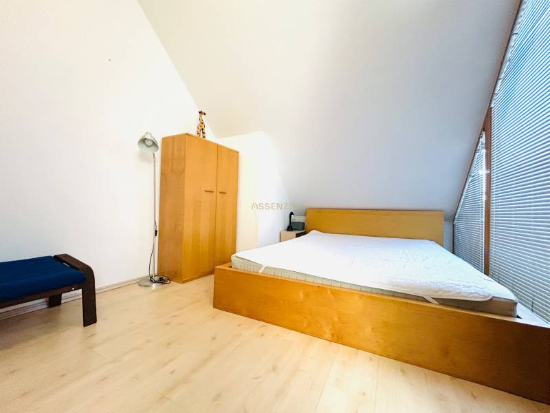 Hálószoba egy kétszobás lakásban, fa dekor padlóval, ággyal és szekrénnyel.