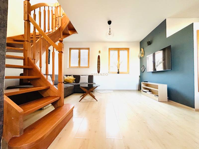 Nappali szoba fa lépcsőkkel, fa dekor padlóval és televízióval egy kétszobás lakásban.