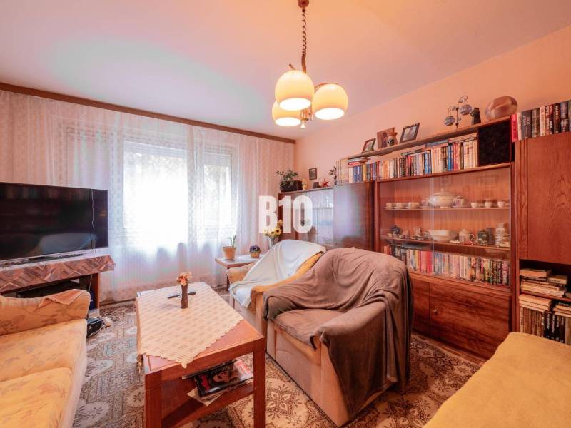 Nappali egy kétszobás lakásban kárpitozott kanapéval és szekrénysorral.