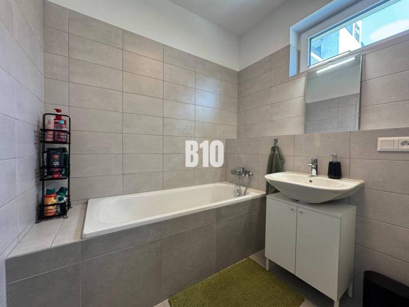 Fürdőszoba egy kétszobás lakásban káddal, mosdóval és világos csempékkel.