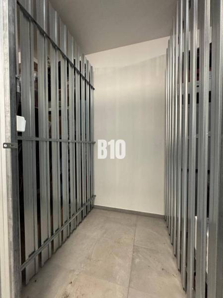 Rácsos tárolóhely betonpadlóval egy kétszobás lakásban.