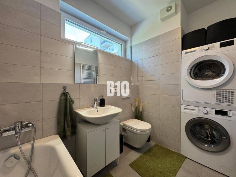 Fürdőszoba káddal, mosógéppel és szárítógéppel egy kétszobás lakásban.