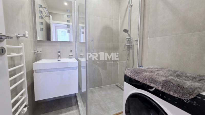 Fürdőszoba egy kétszobás lakásban mosdóval, zuhanyzóval és mosógéppel.