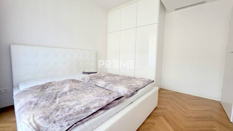 Hálószoba egy kétszobás lakásban ággyal, fehér szekrénnyel és fa dekorációjú padlóval.