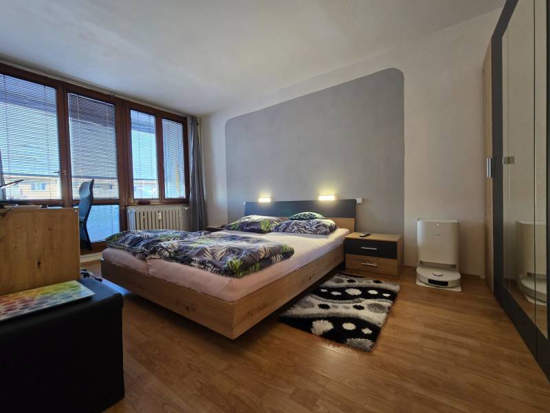 Hálószoba ággyal és bútorokkal, fa dekorációjú padló, világos árnyalatok.