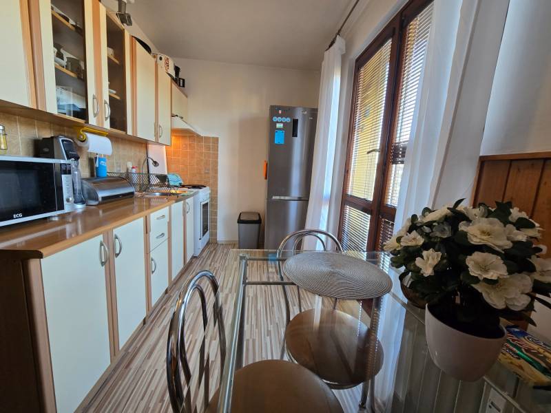 Konyha egy kétszobás lakásban pulttal, konyhaszekrénnyel és üvegasztallal.