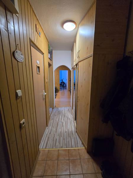 Folyosó egy kétszobás lakásban fa fallal és csempével a padlón.