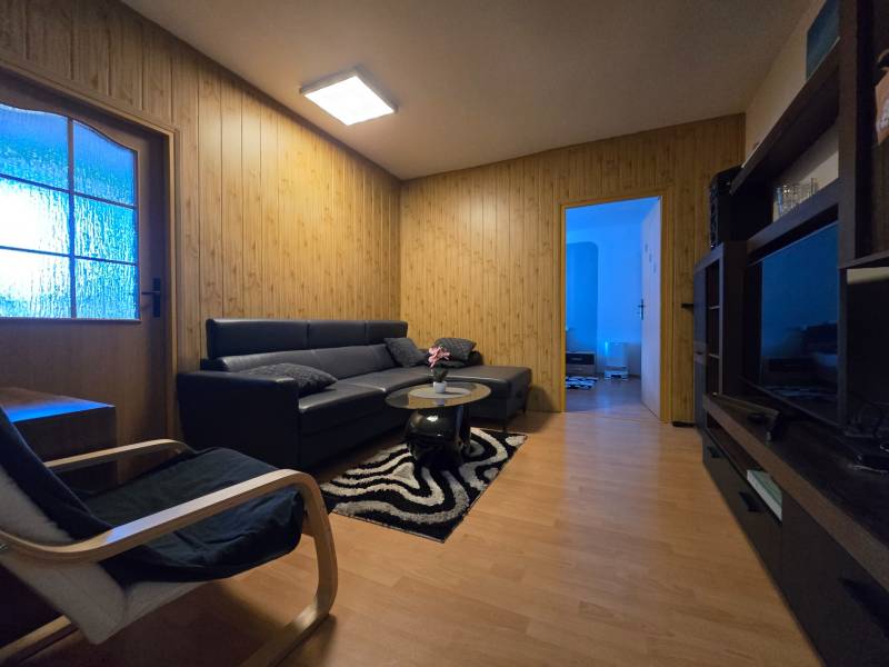 Nappali egy kétszobás lakásban, fa dekor padlóval és kényelmes ülőgarnitúrával.