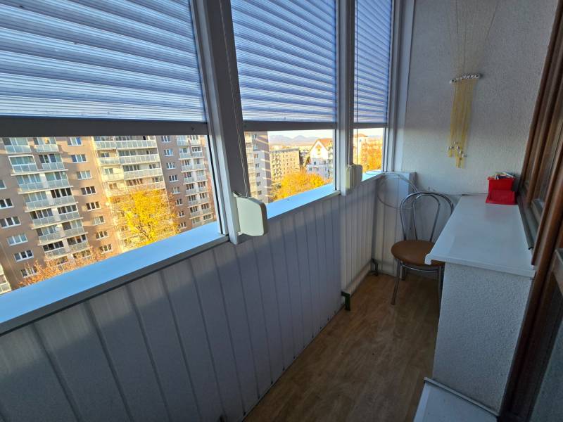 Üvegezett erkély egy 2 szobás lakásban, kilátással az épületekre, fa dekorációjú padlóval.