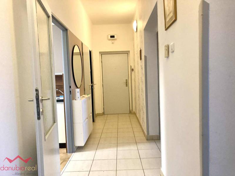 Folyosó egy 3 szobás lakásban világos csempékkel és tükörrel a falon.