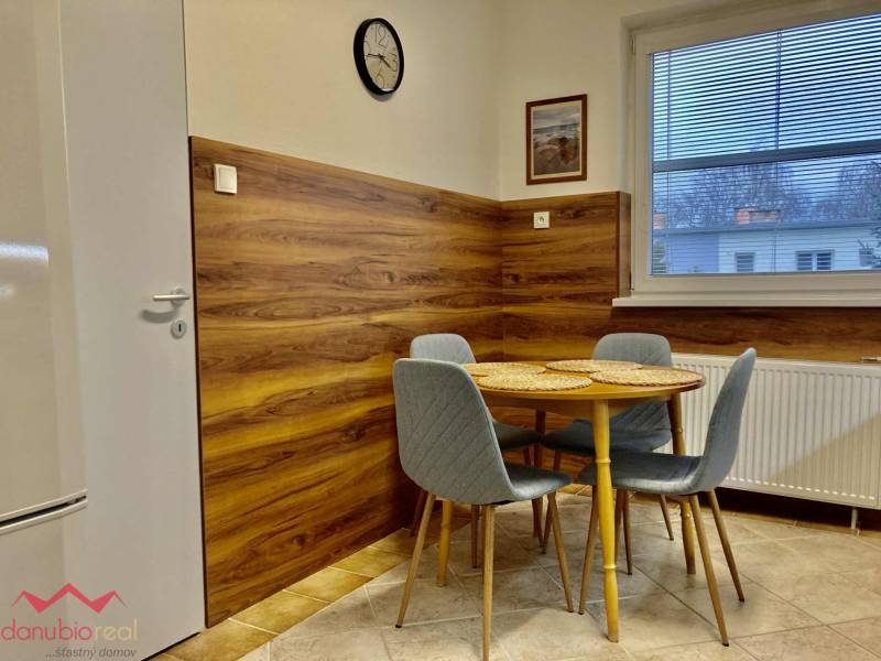 Konyha étkezőasztallal, szürke székek, fa mintázatú padló, 3 szobás lakás.