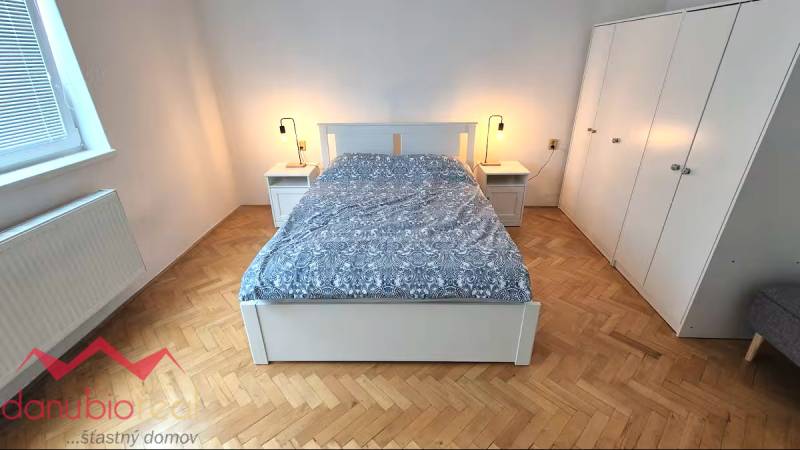 Hálószoba ággyal, éjjeliszekrényekkel és szekrénnyel, fa dekoros padlóval.