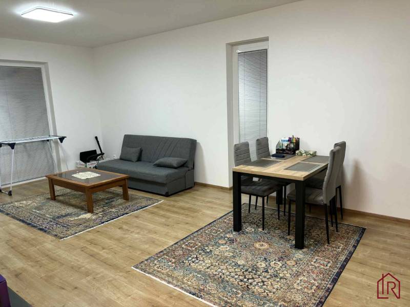 Nappali étkezőasztallal, szürke kanapéval és fa dekorációjú padlóval egy kétszobás lakásban.