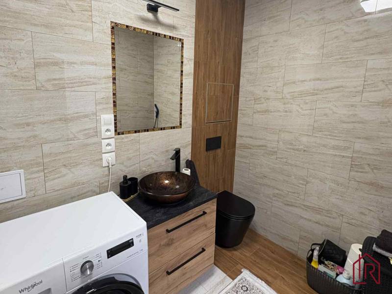 Fürdőszoba kerámia mosdóval és mosógéppel egy kétszobás lakásban, fa dekoros padlóval.