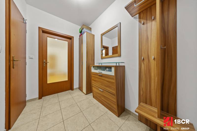 Folyosó egy kétszobás lakásban fa bútorokkal és fa dekorációs burkolattal.