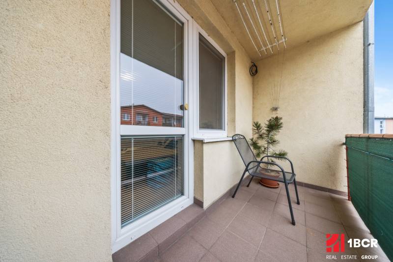 A Veltlínska utcai kétszobás lakás erkélye Pezinkben, virággal és székkel.