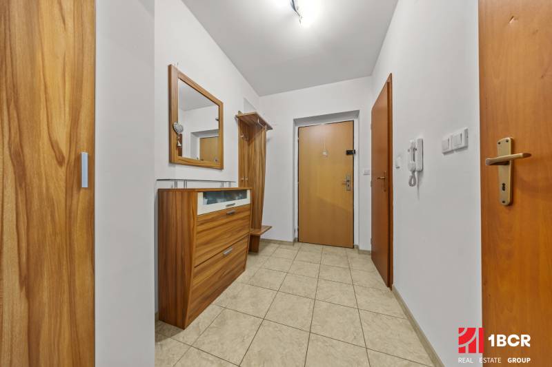 Előszoba egy kétszobás lakásban csempével és fa bútorokkal.