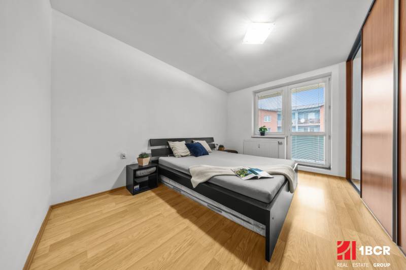 Hálószoba egy kétszobás lakásban ággyal, éjjeliszekrényekkel és fa dekorációjú padlóval.