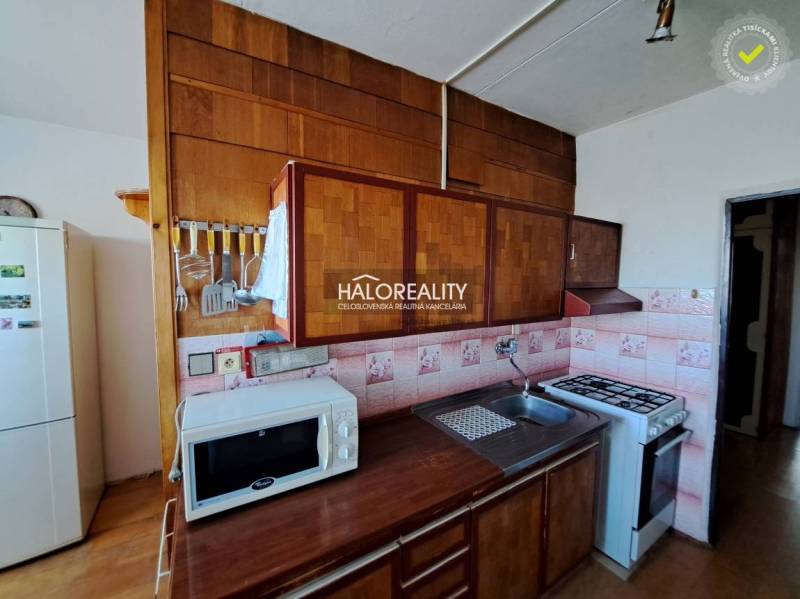 Nappali egy háromszobás lakásban kanapékkal, fa dekor padlóval és nagy ablakokkal.