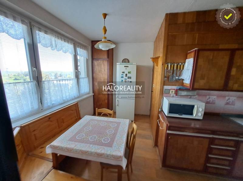 Nappali egy háromszobás lakásban, fa mintázatú padlóval, ülőgarnitúrával és fali dekorációkkal.