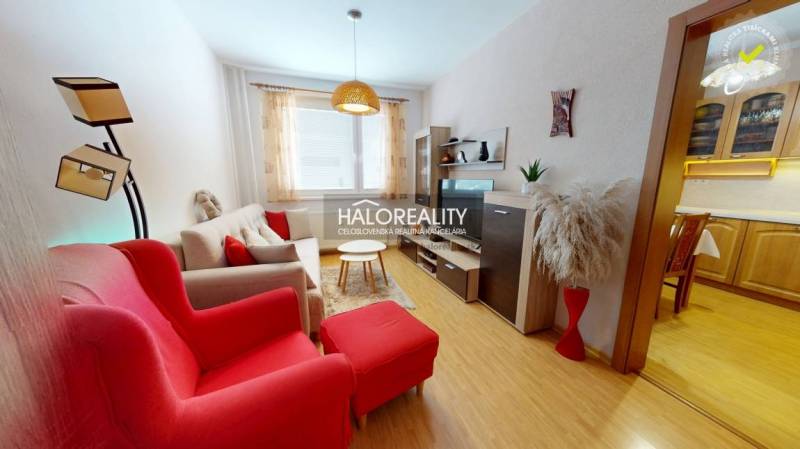 Nappali egy kétszobás lakásban, fa dekoros padlóval és piros fotelekkel.