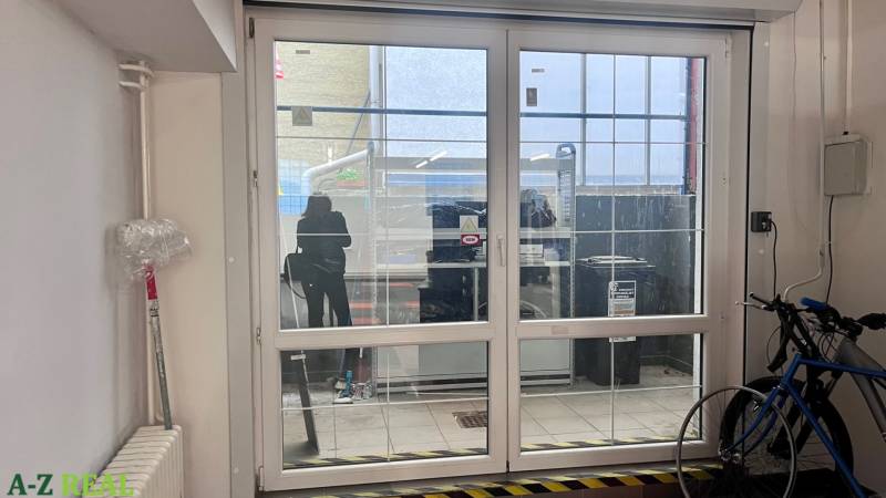 Üveg tolóajtók üzlethelyiségekben, kerékpár, radiátor és műanyag fólia a falon.