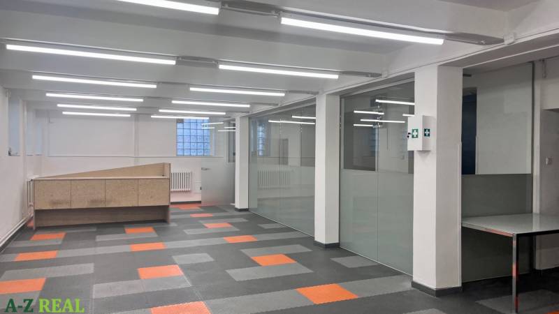 Üzlethelyiség üvegfalakkal és fa mintás padlóval.