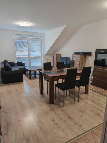 Nappali egy háromszobás lakásban, fa dekoros padlóval és étkezőasztallal.