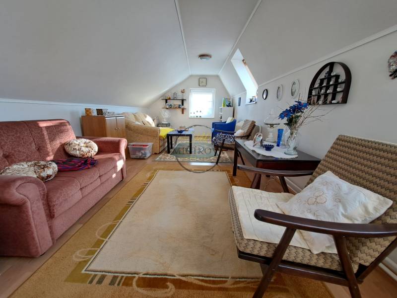 Családi ház tetőtéri nappalija kinyitható kanapéval és dekoratív kiegészítőkkel.