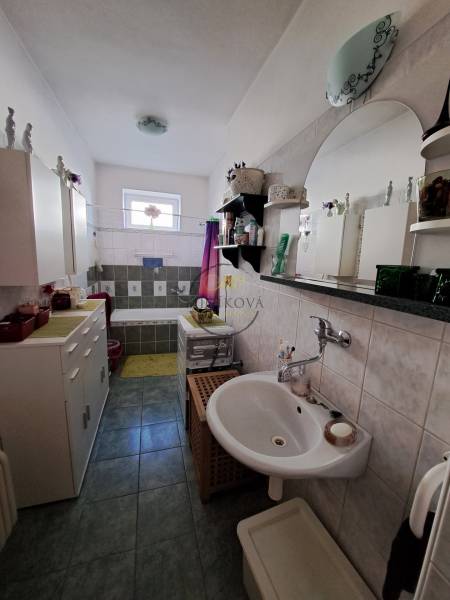 Családi ház fürdőszobája zuhanyzóval, mosdóval és szekrényekkel.