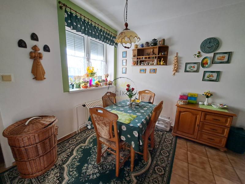 Étkező sarok családi házban, fa bútorokkal, díszített falakkal és szőnyegekkel.