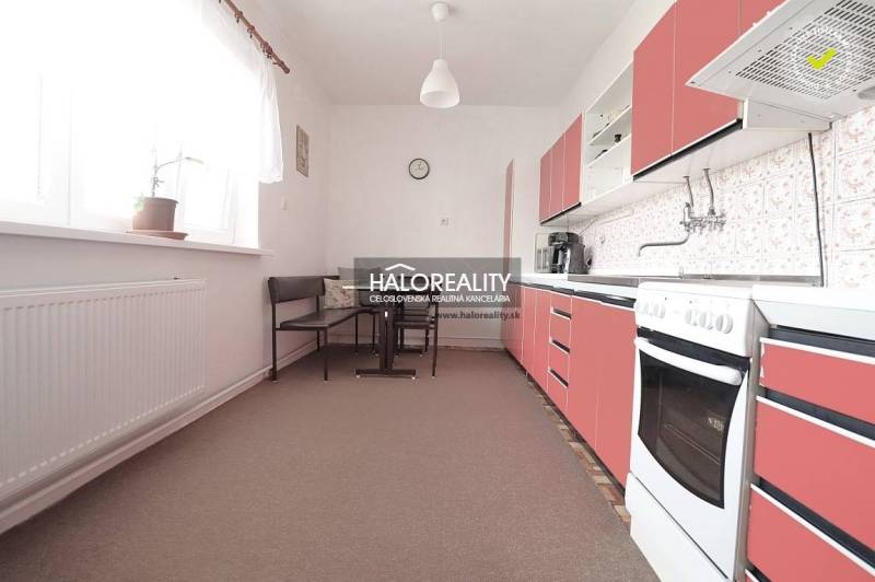 Konyha családi házban piros szekrényekkel és étkező sarokkal.