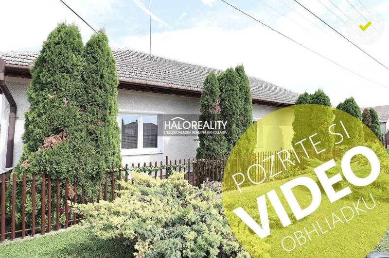 Családi ház Nagykéren gondozott kerttel, zöld tujafákkal és kerítéssel.