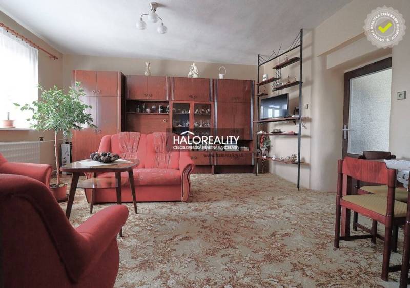 Nappali családi házban fotelekkel, vitrinnel és szőnyeggel.