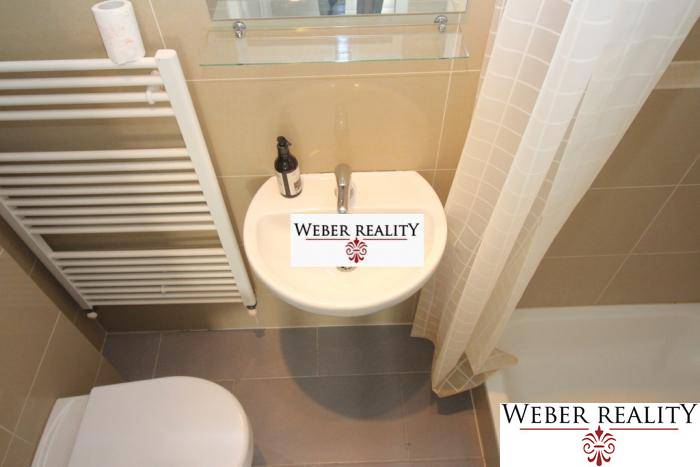 Fürdőszoba egy kétszobás lakásban zuhanyzóval és kerámia mosdóval.