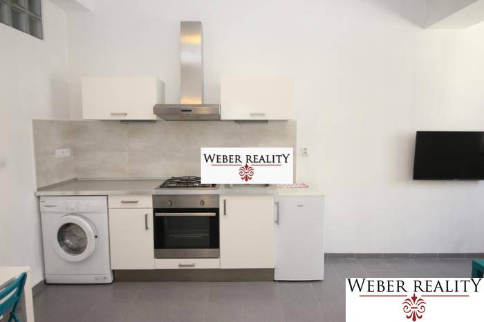 Konyha egy 2 szobás lakásban háztartási gépekkel és falra szerelt televízióval.