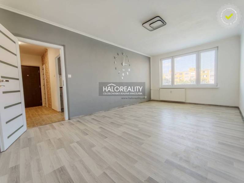 Nappali egy kétszobás lakásban, fa dekoros padlóval és nagy ablakokkal.